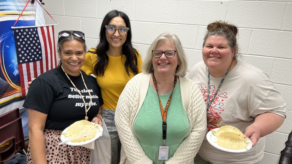 Four staff members pose for a photo at a staff appreciation taco bar. 