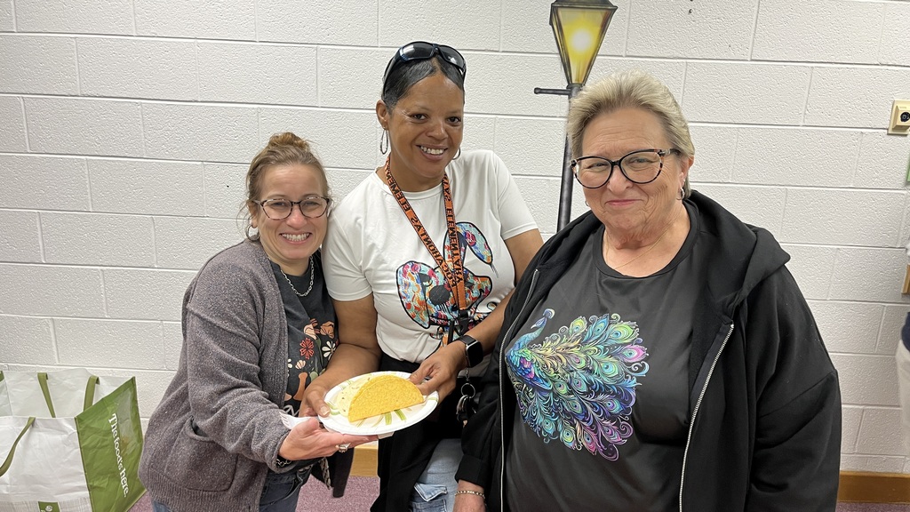 Three staff members pose for a photo at a staff appreciation taco bar. 