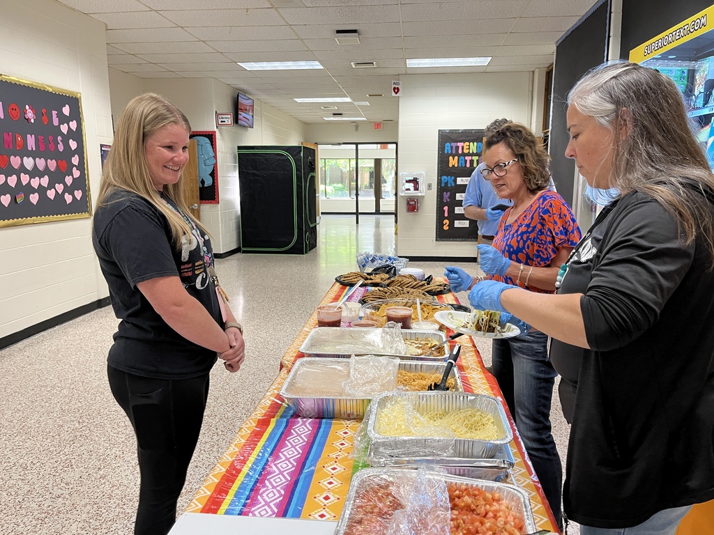 A staff member is served by central office staff at a staff appreciation taco bar at her school.