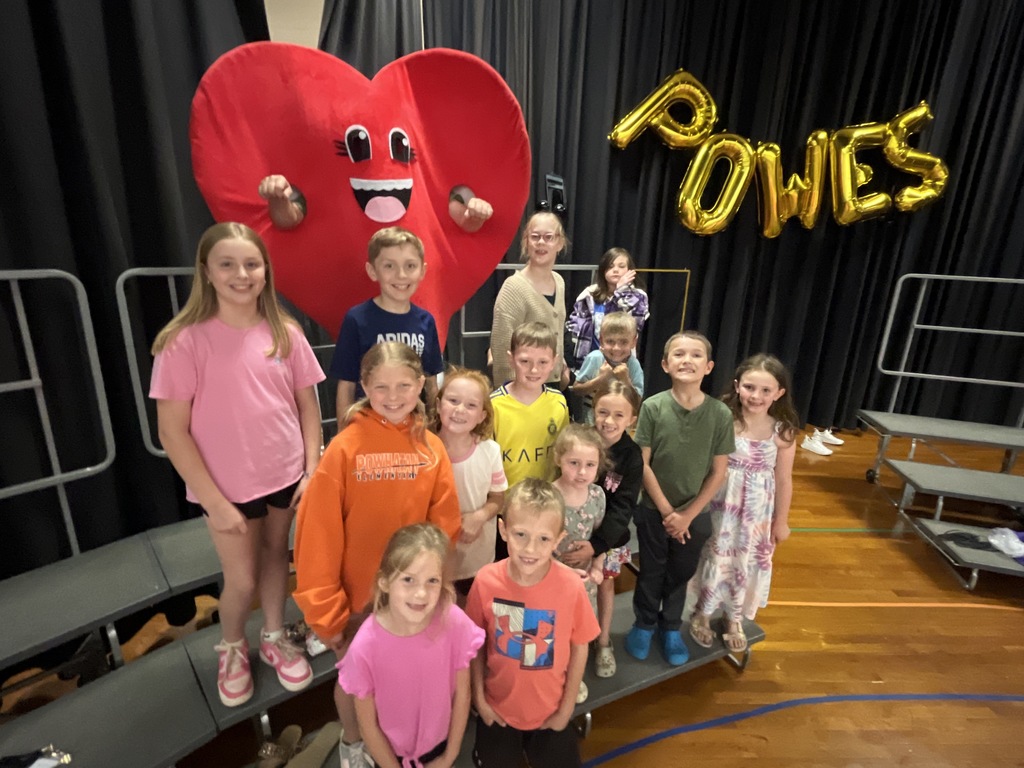 A group of students pose for a photo with a person in a heart costume.