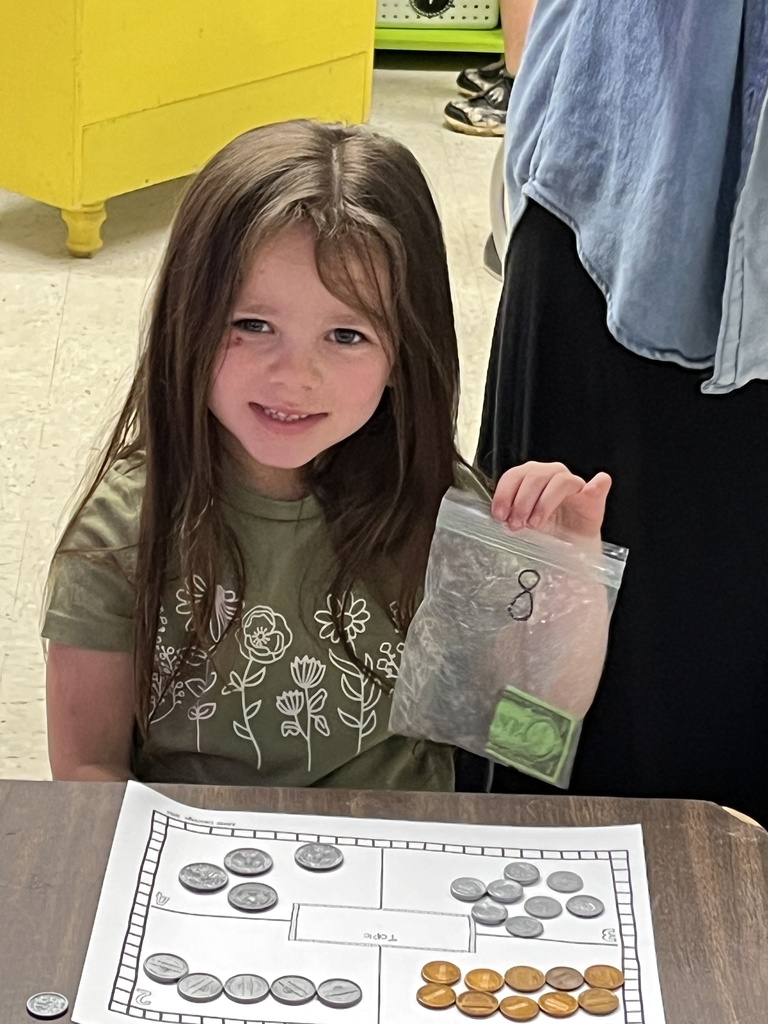 A kindergartner learns about the value of money by working with replica coins.