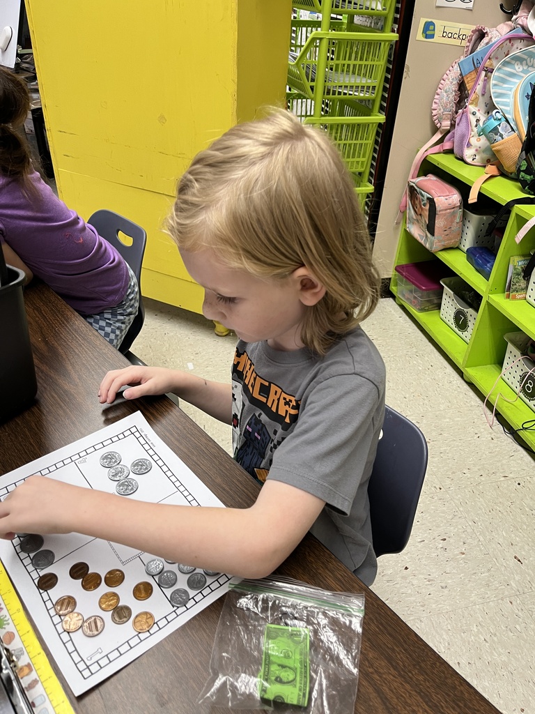 A kindergartner learns about the value of money by working with replica coins.