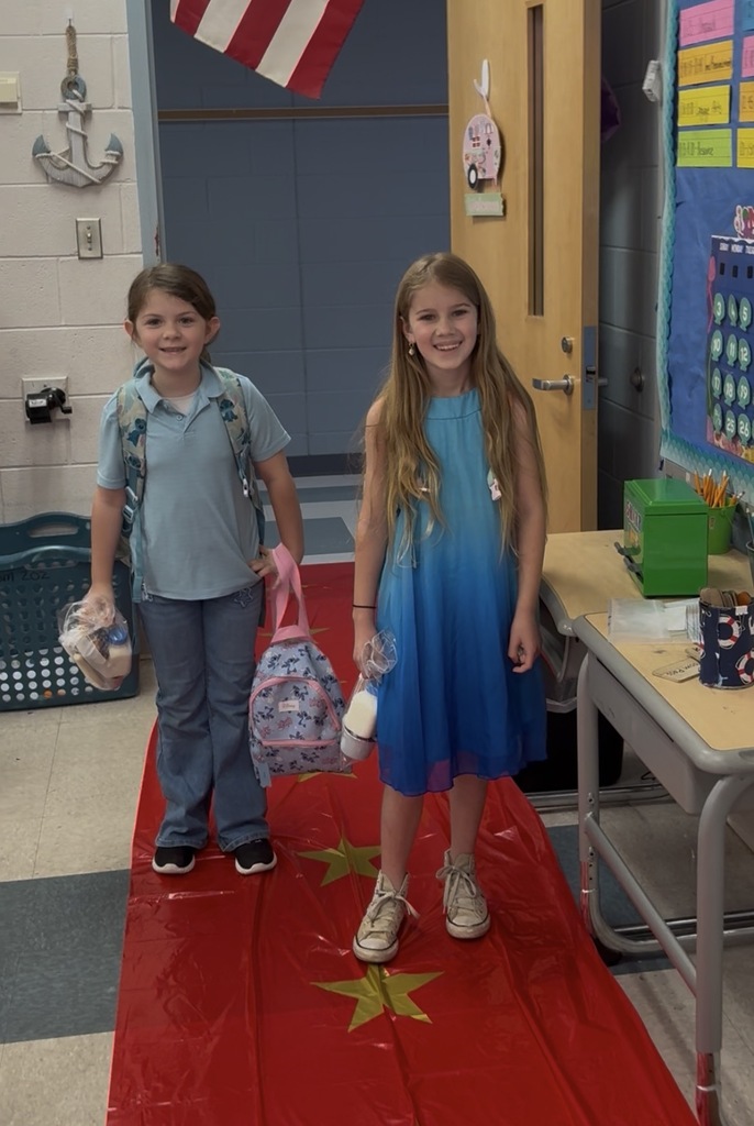 Students enter a classroom decorated for a Hollywood theme day and pose on the red carpet.