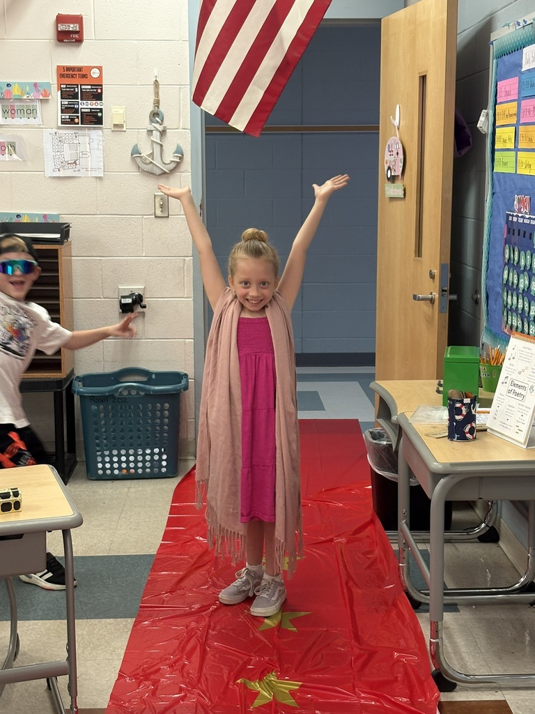 A student enters a classroom decorated for a Hollywood theme day and poses on the red carpet.