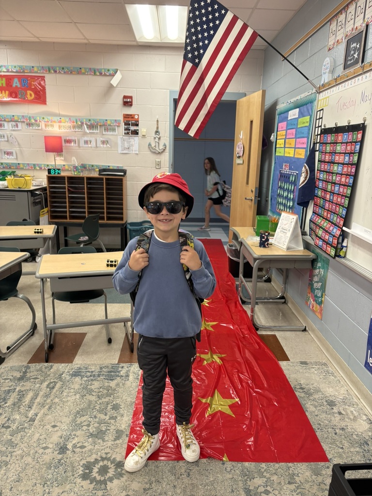 A student enters a classroom decorated for a Hollywood theme day and poses on the red carpet.