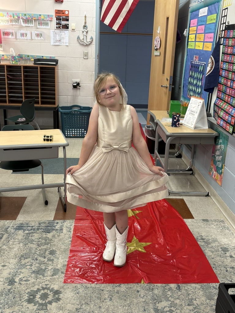 A student enters a classroom decorated for a Hollywood theme day and poses on the red carpet.