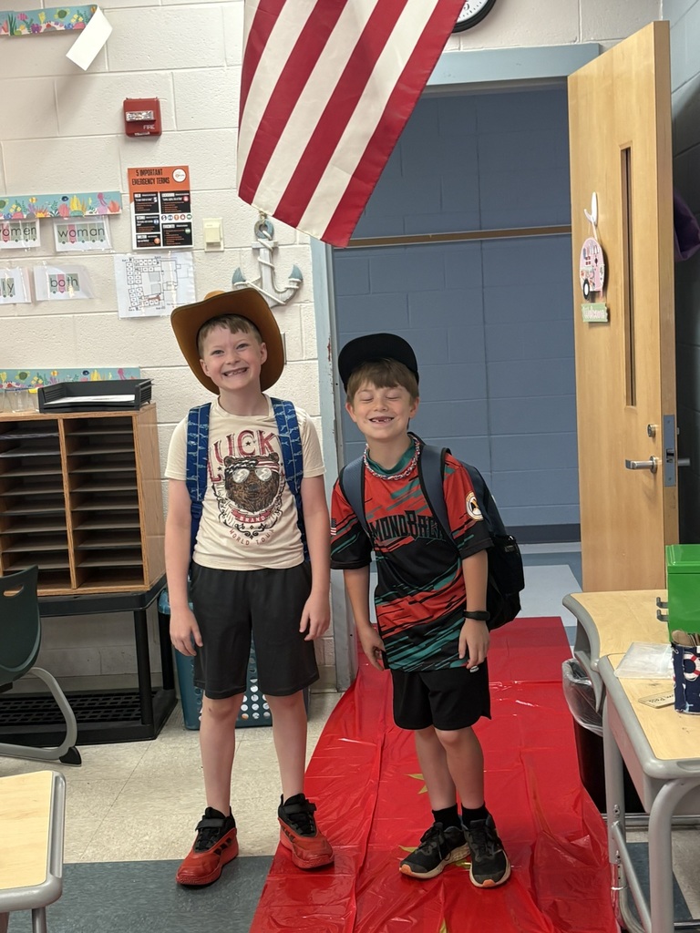 Students enter a classroom decorated for a Hollywood theme day and pose on the red carpet.