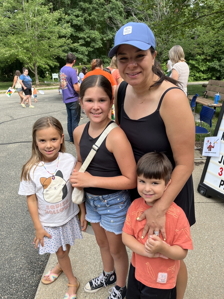 An adult and three children pose for a photo at a summer reading program kickoff event.