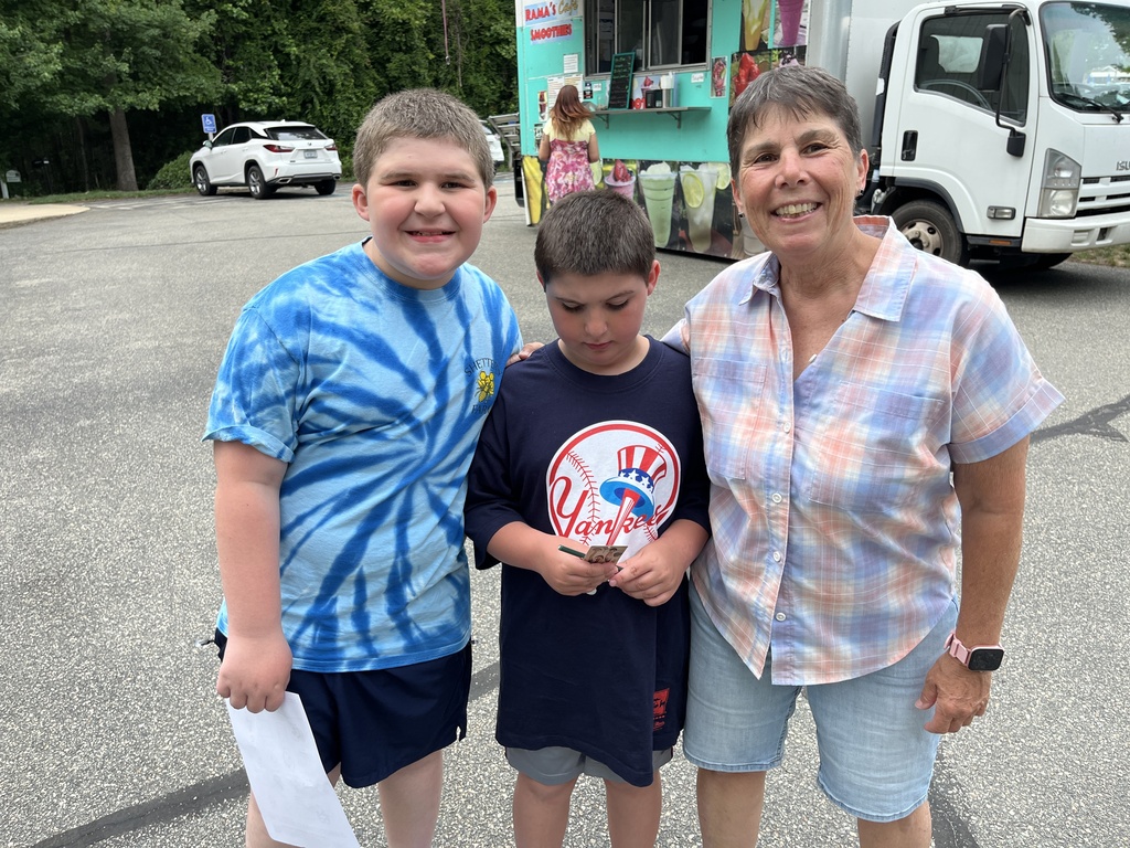 An adult and two children pose for a photo at a summer reading program kickoff event.
