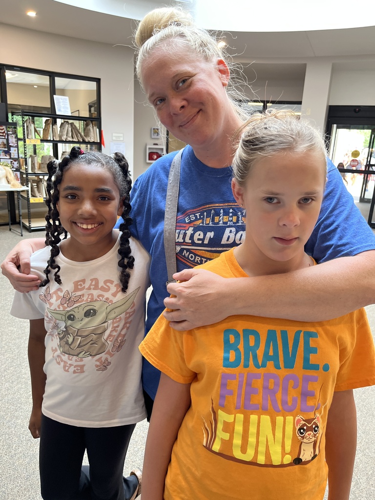 An adult and two children pose for a photo at a summer reading program kickoff event.