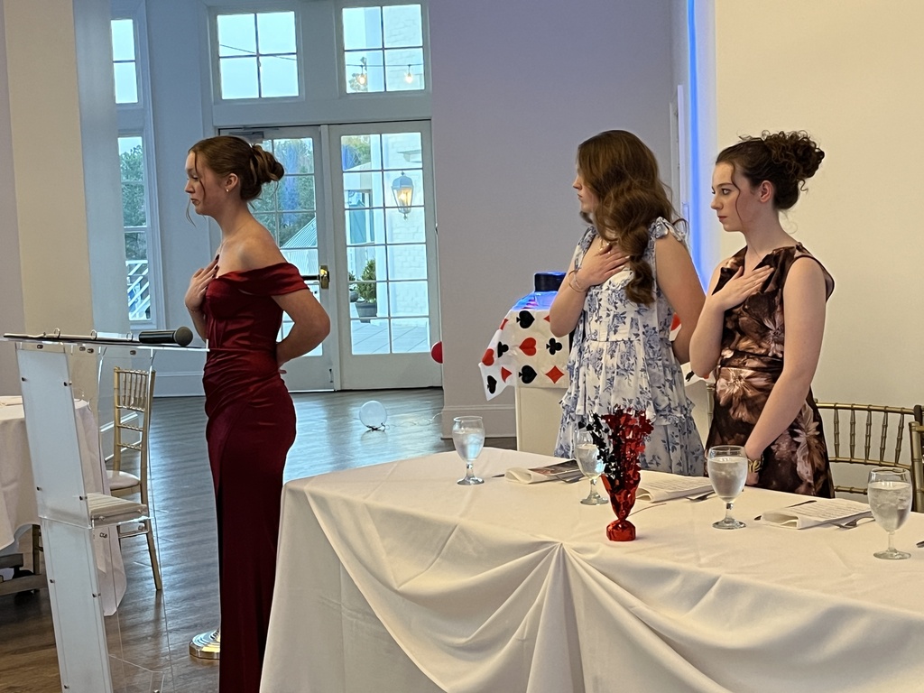 A group of students in formal dress stand for the presenting of the colors during a JROTC military ball.