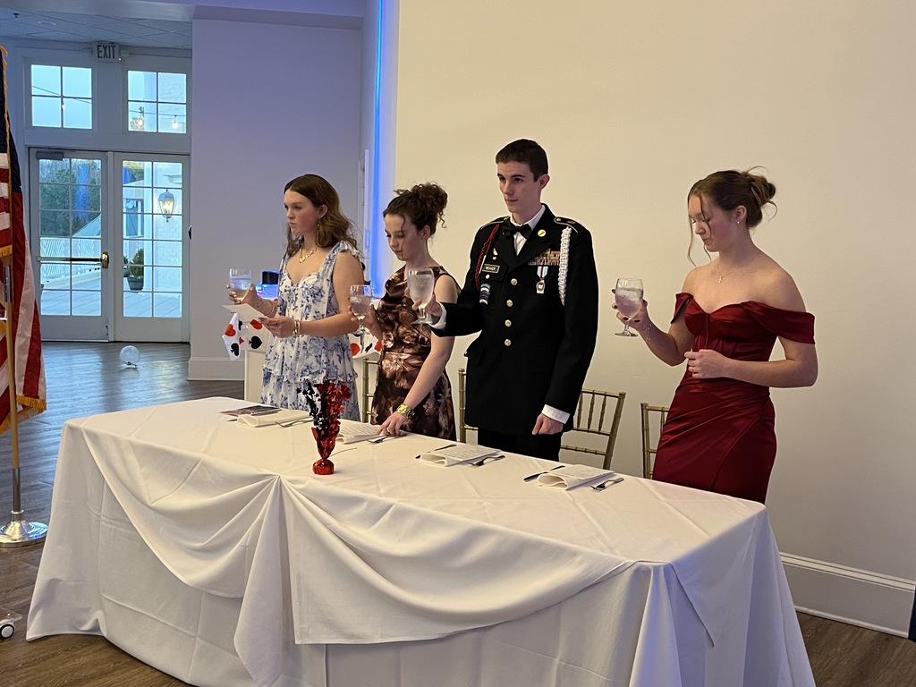 Cadets in formal dress stand for a toast during a JROTC military ball.