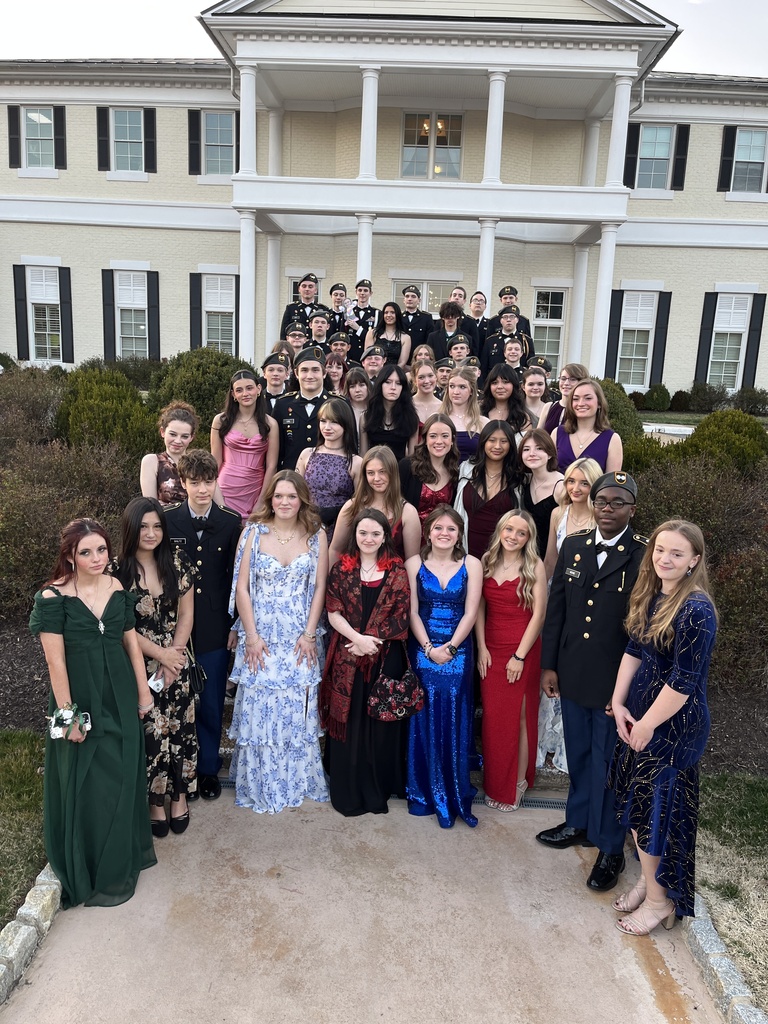 A large group of students in JROTC uniform and formal dress pose for a group photo.
