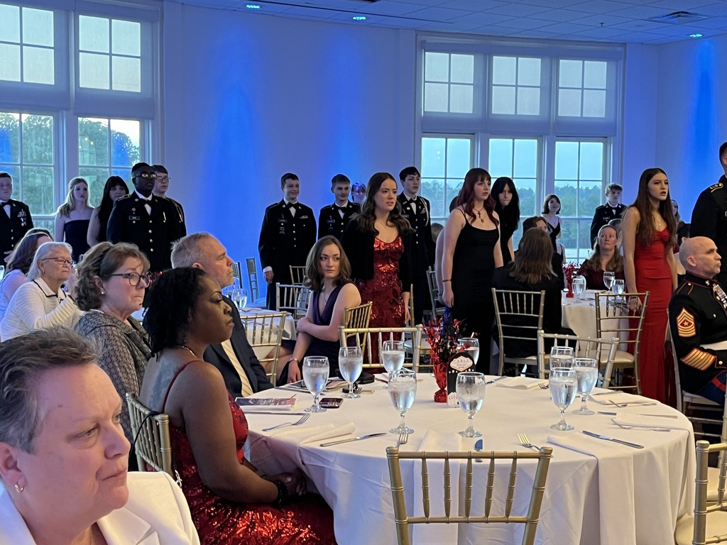 Cadets in formal dress stand to be recognized during a JROTC military ball.