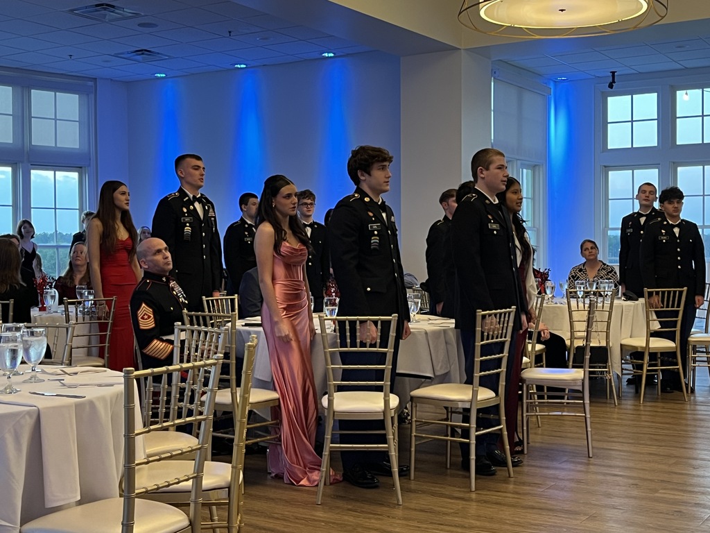Cadets in formal dress stand to be recognized during a JROTC military ball.