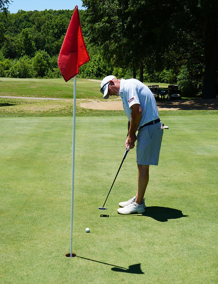 A golfer takes his shot with a golf club during a golf tournament. 