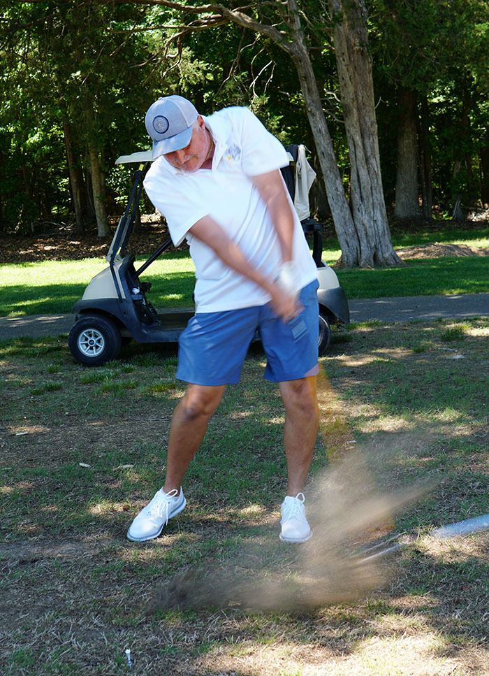 A golfer takes his shot with a golf club during a golf tournament. 