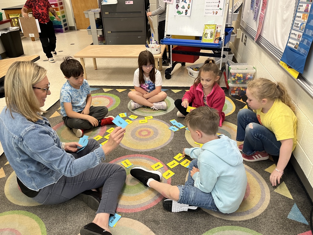 Students work at a literacy station with their teacher to practice long vowel sounds .