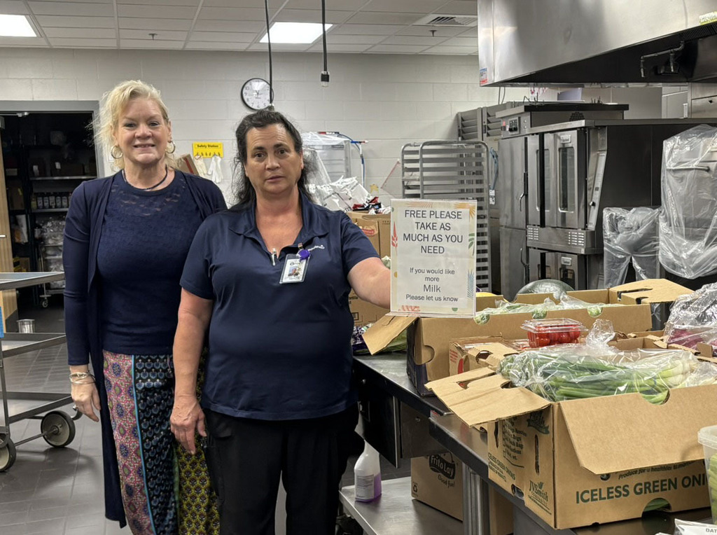 Two women in a kitchen where food is being distributed for a summer meal program.