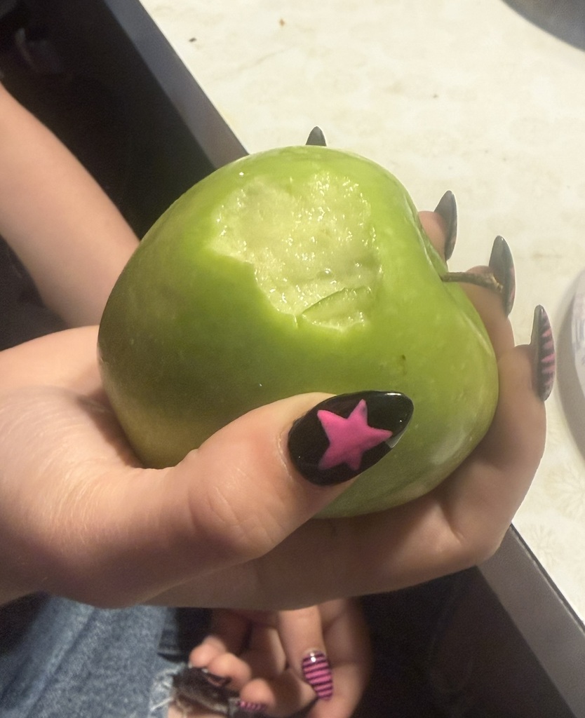 A hand holding an apple with a bite taken out of it.