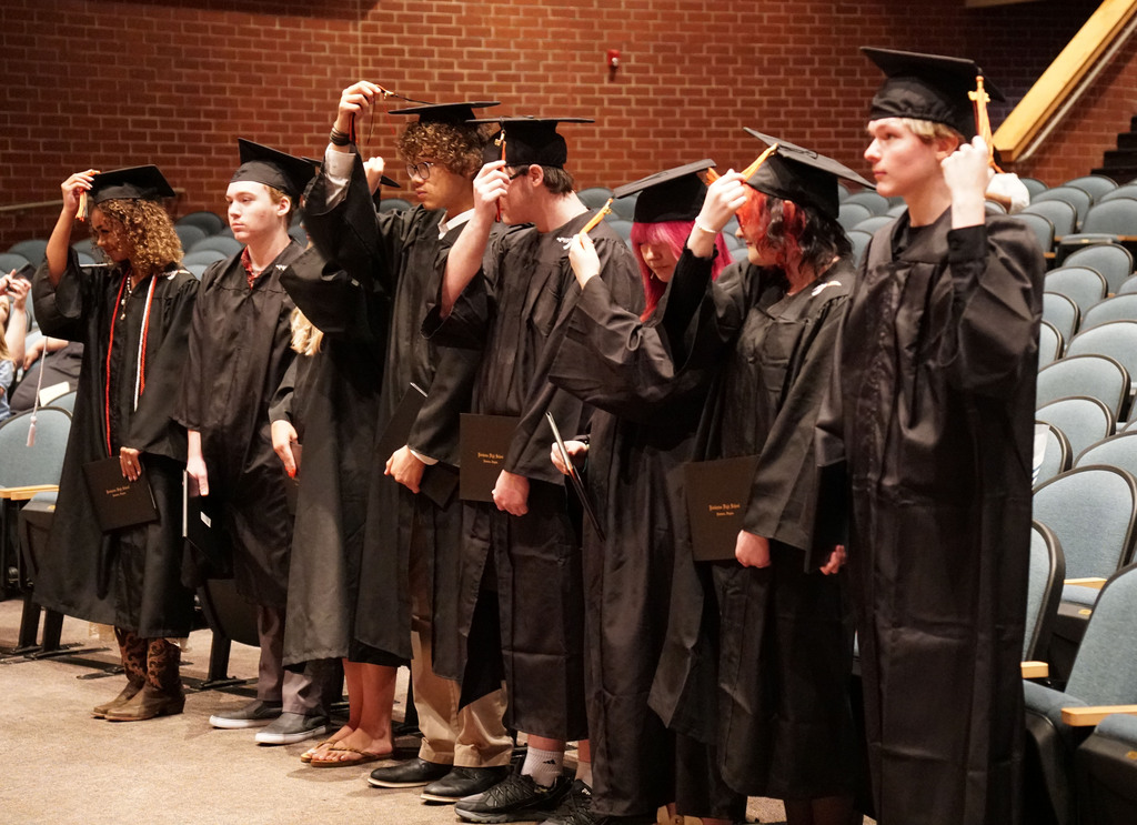 A group of summer graduates move their tassels at the end of a graduation ceremony.