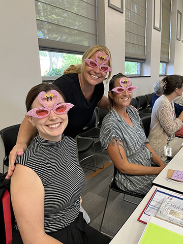 Three new staff members pose for a photo wearing flamingo sunglasses.