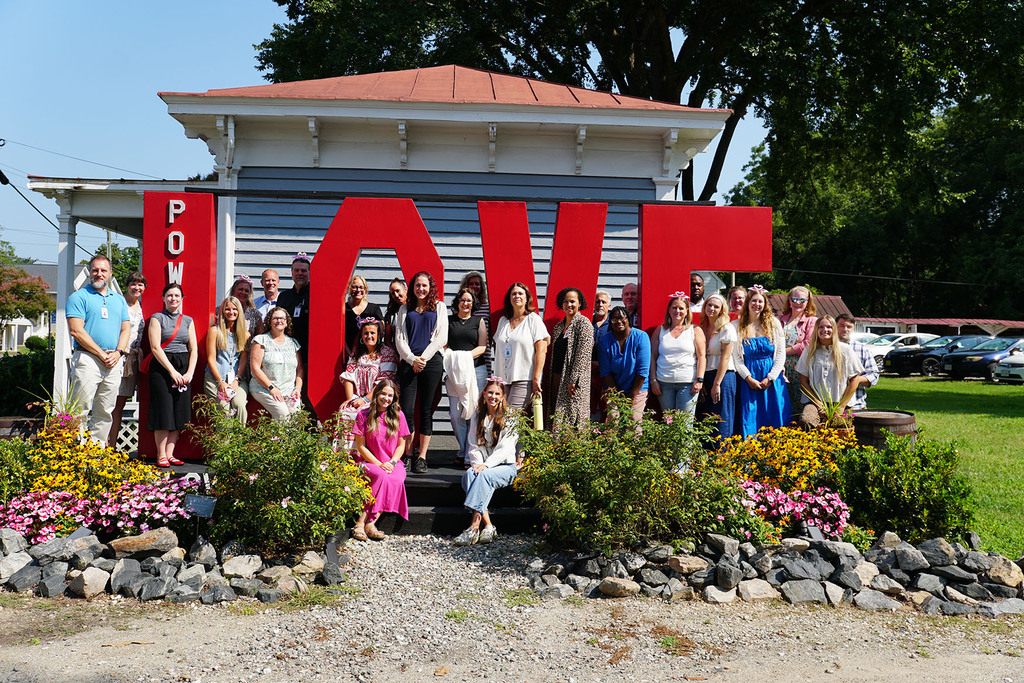 A large group of people pose outside around a giant LOVE sign.