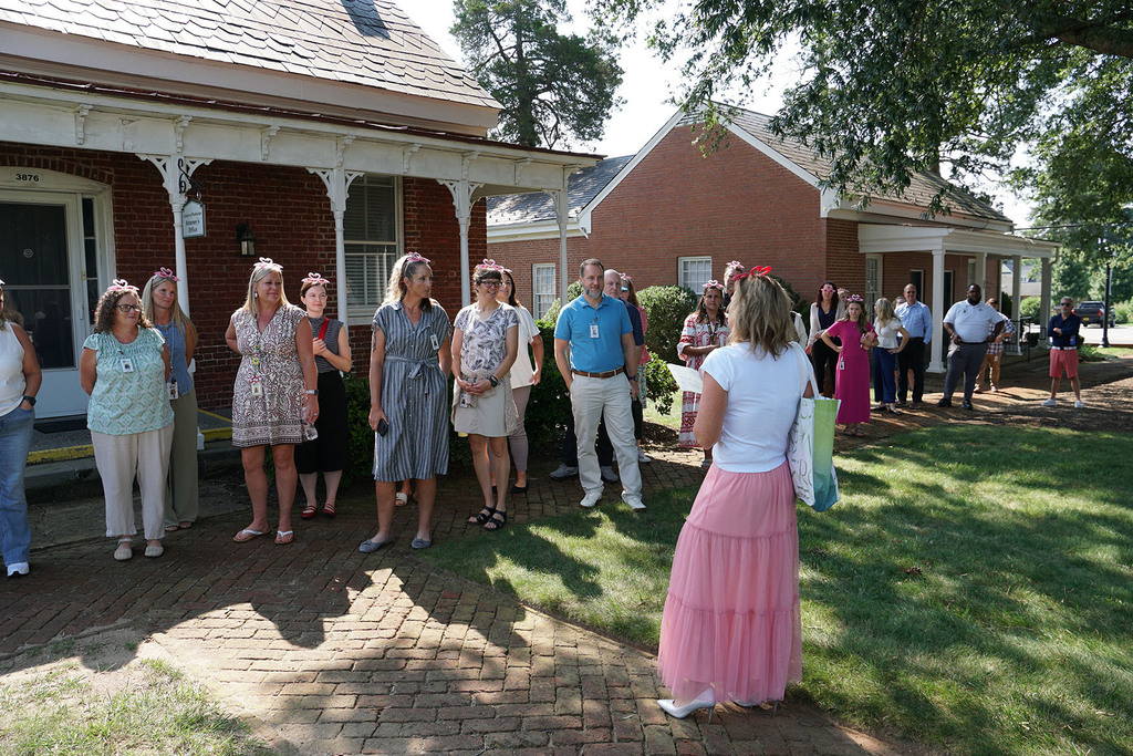 An assistant principal acting as a tour guide talks to new staff members on the county courthouse lawn during a county tour.