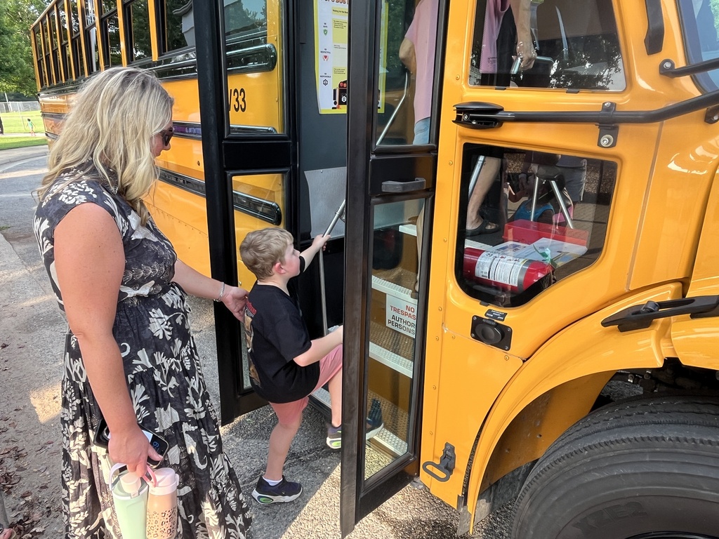 An adult and child enter a bus for a ride at a kindergarten welcome event.