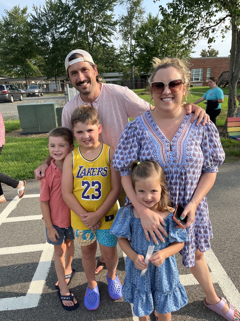Two adults take a photo with three children at a kindergarten welcome event.