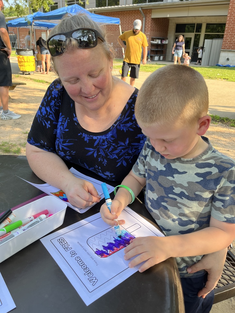 An adult and child pose for a photo at a kindergarten welcome event.