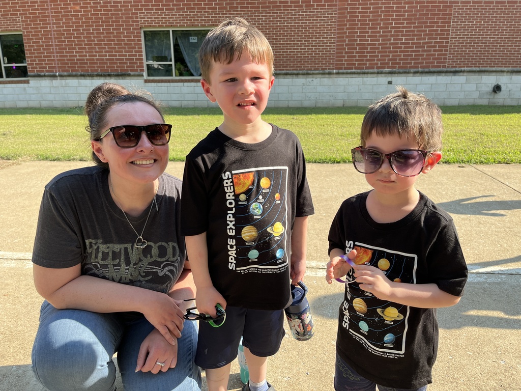 An adult and two children pose for a photo at a kindergarten welcome event.