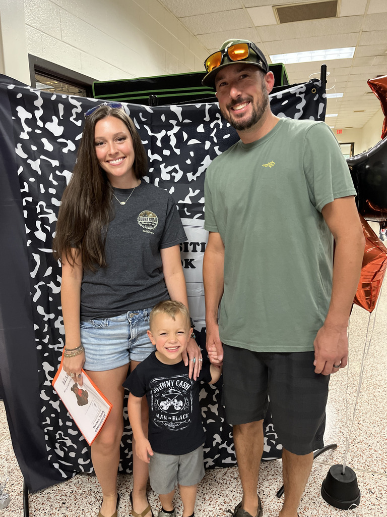 Two adults and a child pose for a photo at a preschool information night.