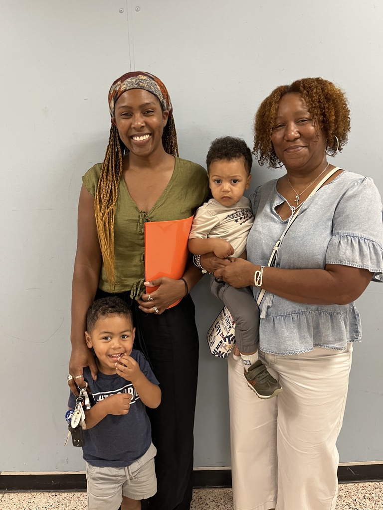 Two adults and two children pose for a photo at a preschool information night.