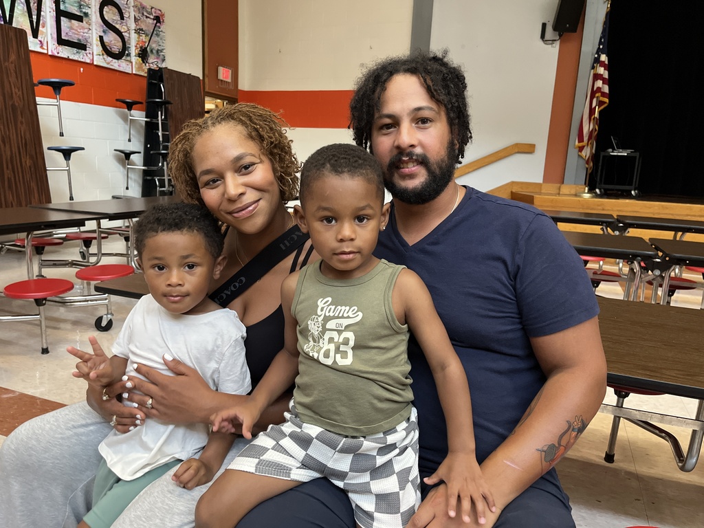 Two adults and two children pose for a photo at a preschool information night.