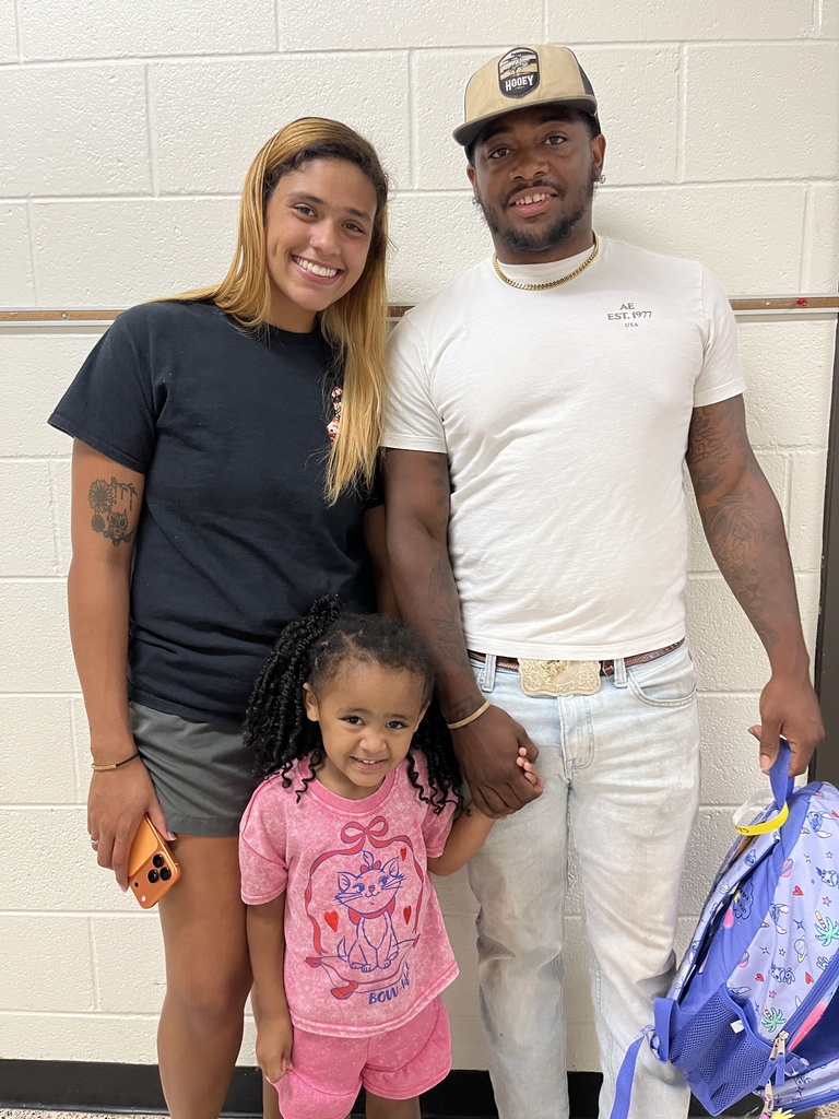 Two adults and a child pose for a photo at a preschool information night.