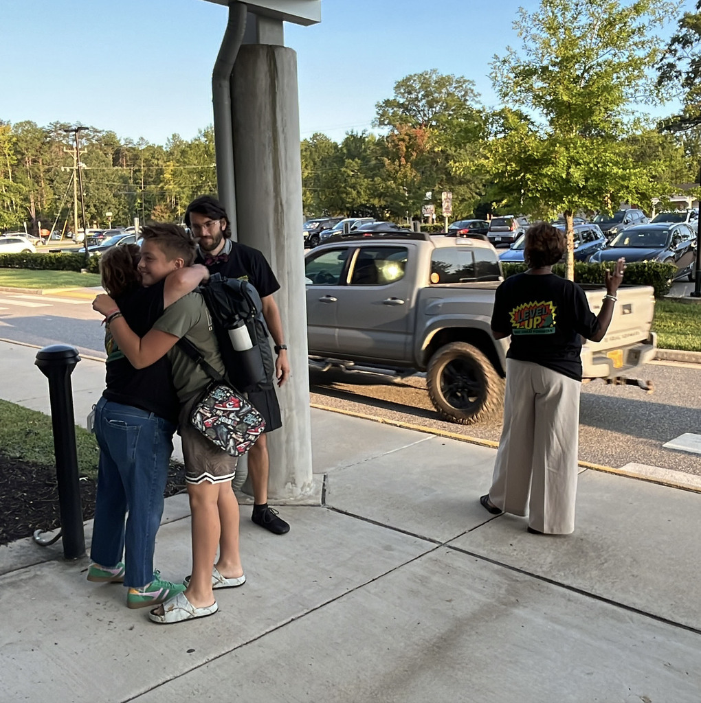 Middle school staff members greet arriving students on the first day of school.