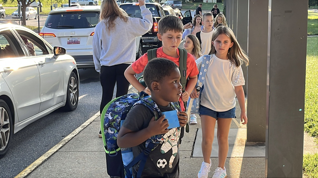 Students arrive via car for the first day of school.