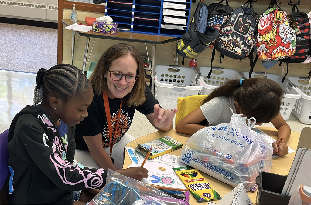 An adult helps students on the first day of school. 