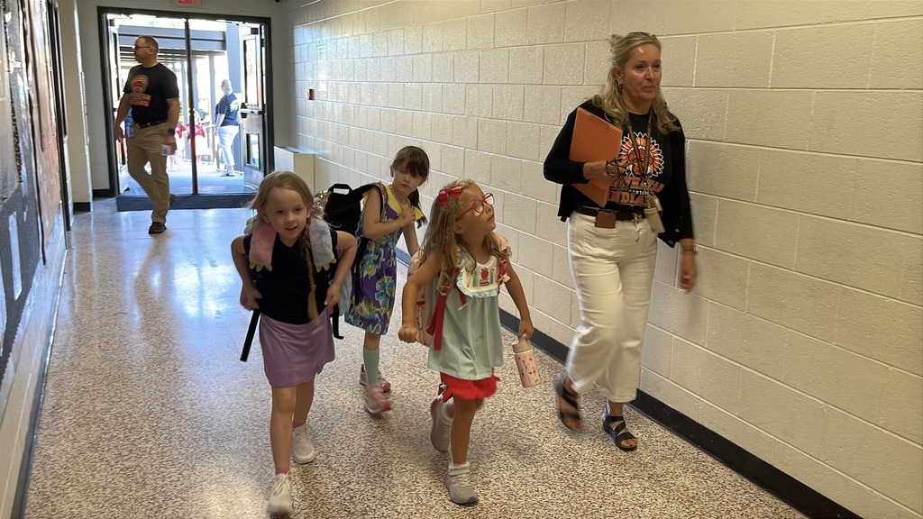 An staff member walks children to their classroom on the first day of school. 