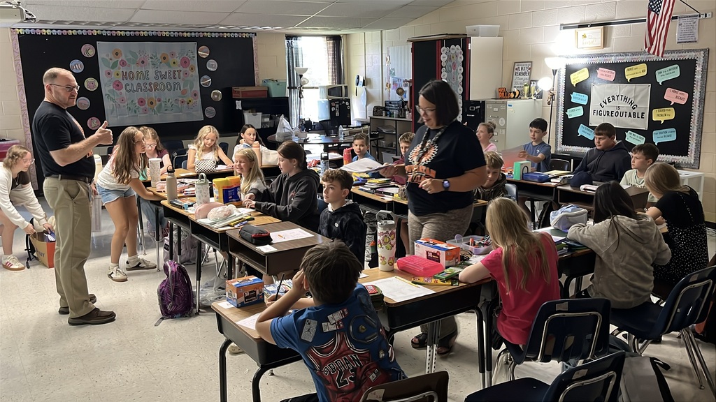 A teacher gives instructions to a classroom on the first day of school.  Ad administrator visits.