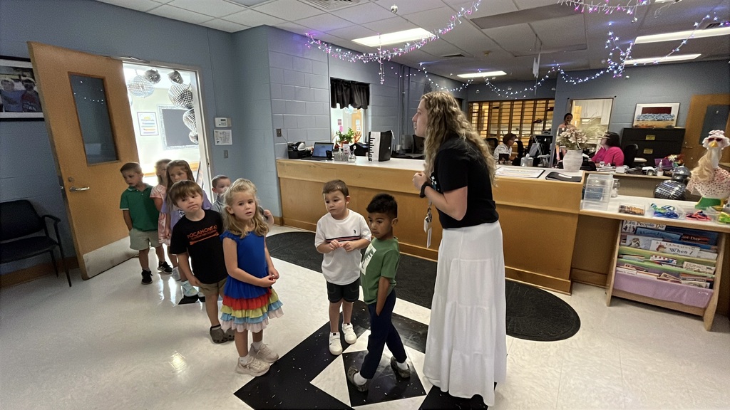 A teacher gives a group of students a school tour on the first day of school.
