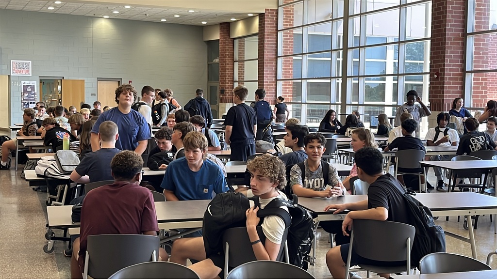 Freshmen sit at cafeteria tables while waiting on the first day of school.