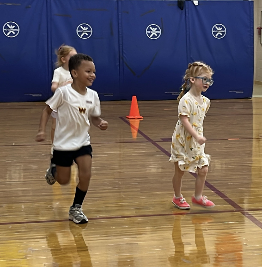 Students run in a school gym on the first day of school.
