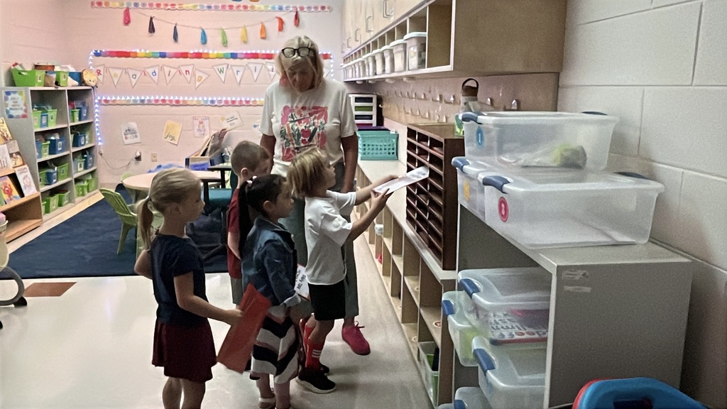A teacher shows students how to stow their folders.