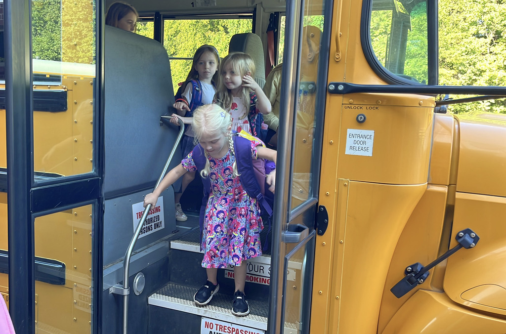 Students exit a bus to go to school.
