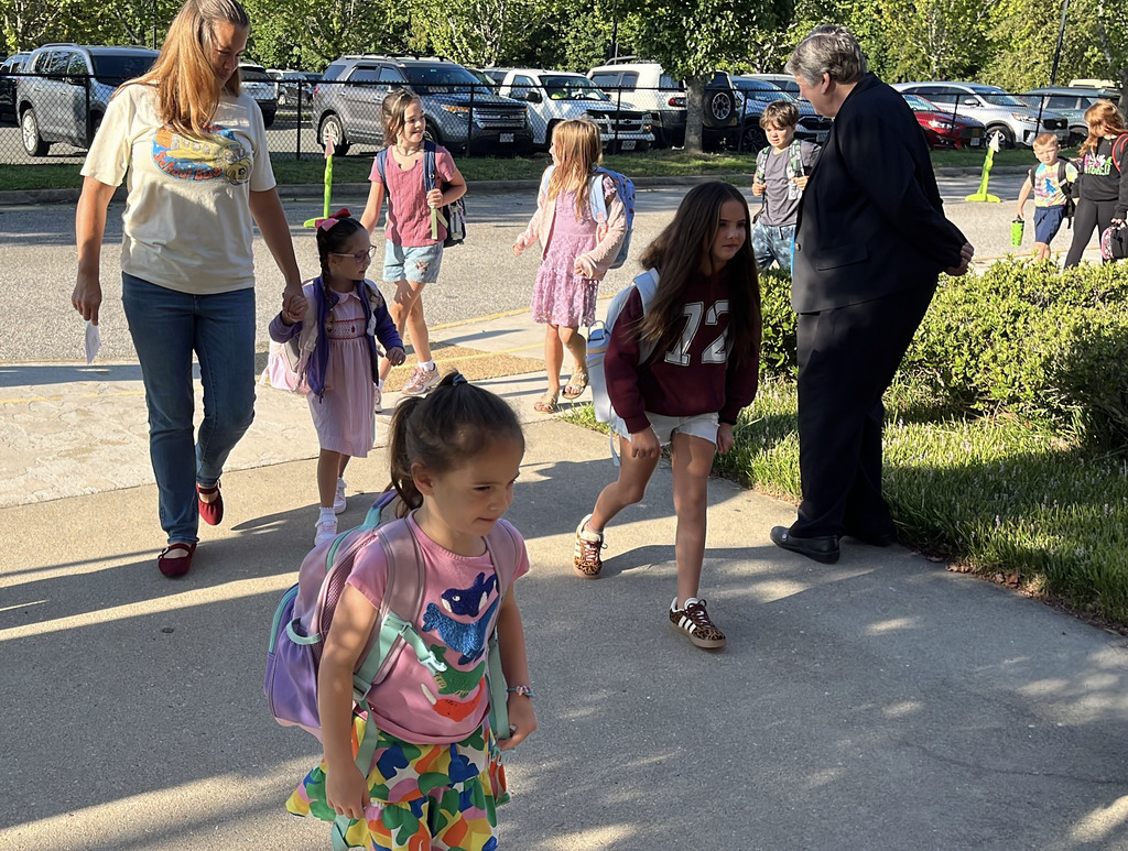 Students walk into school. Adults help.