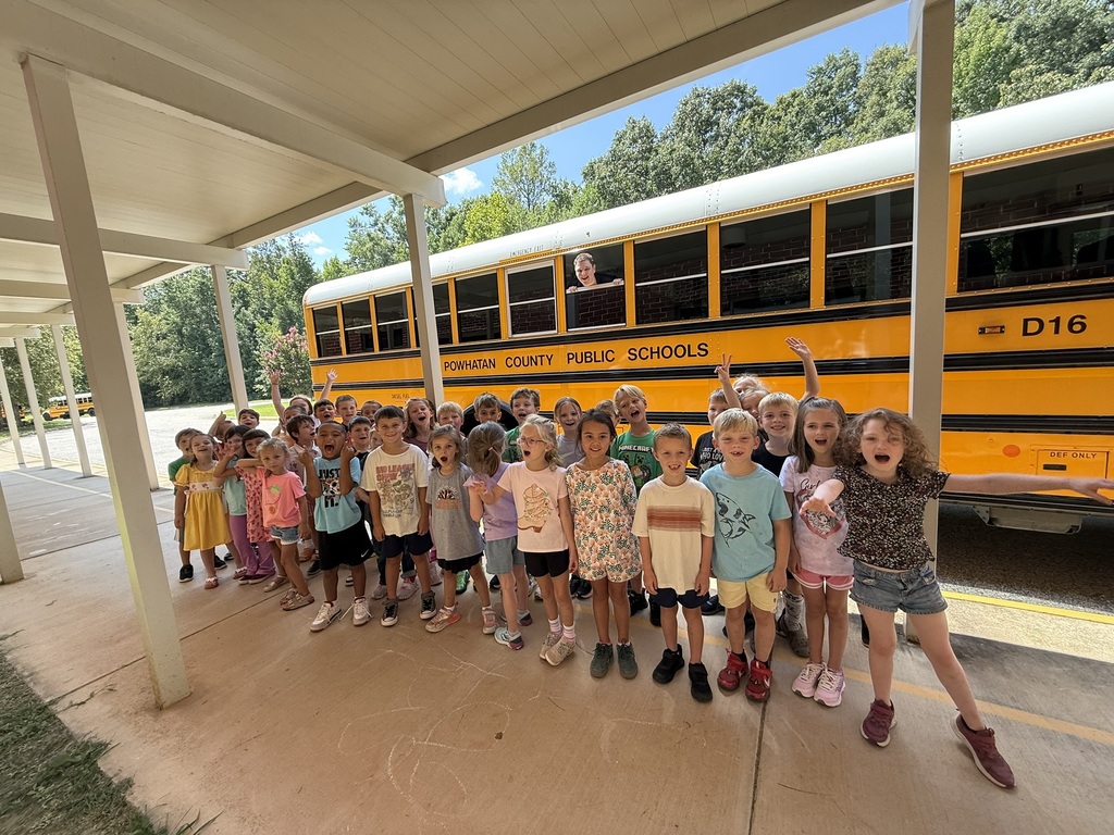 A group of students pose for a photo in front of a school bus.