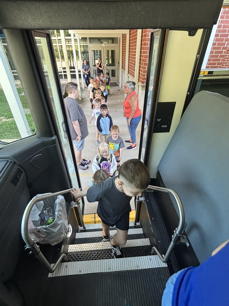 A group of students walk toward the open door of a school bus to climb aboard. 