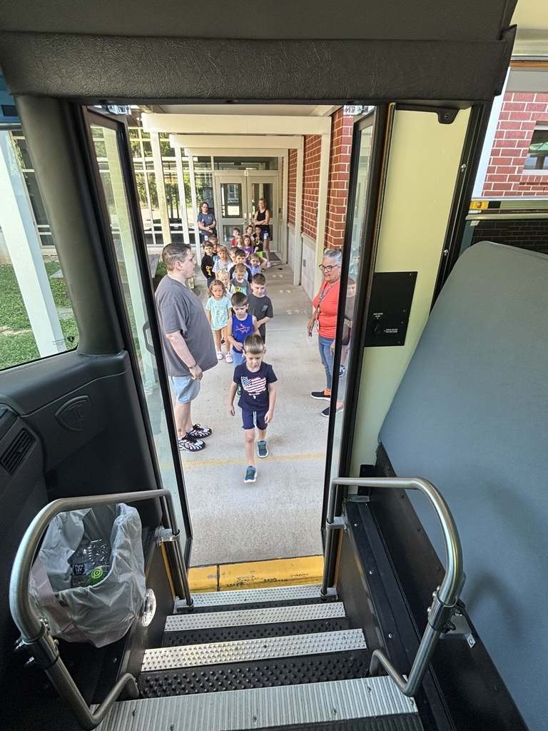 A group of students walk toward the open door of a school bus to climb aboard. 